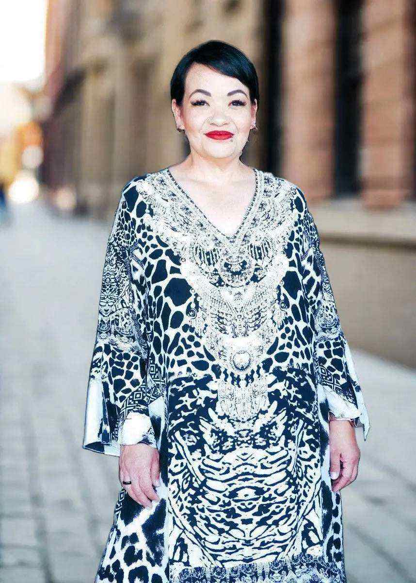 Woman wearing black and white silk hi-low frill dress with handsewn beadwork and long split sleeves