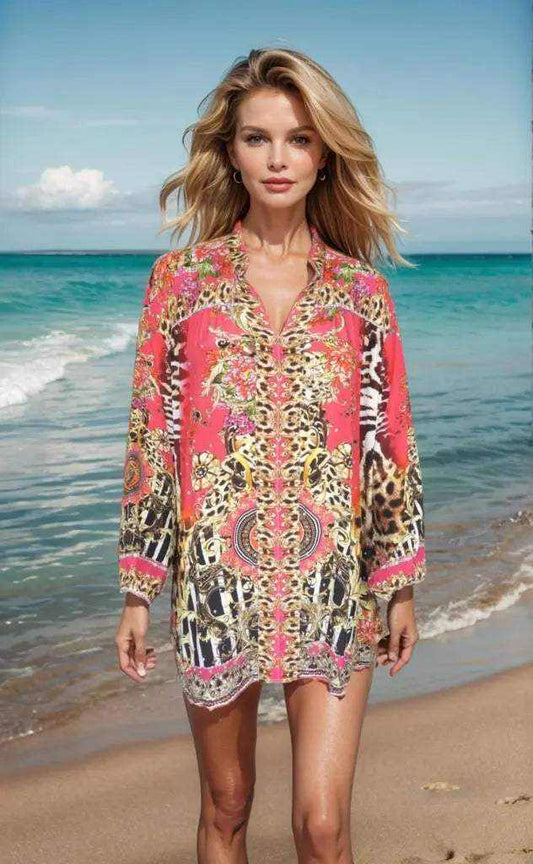 Woman wearing Garden Delight red silk embellished shirt with animal print standing on beach shore