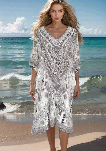 Woman wearing a 34 sleeve silk embellished dress with handsewn beadwork standing on the beach