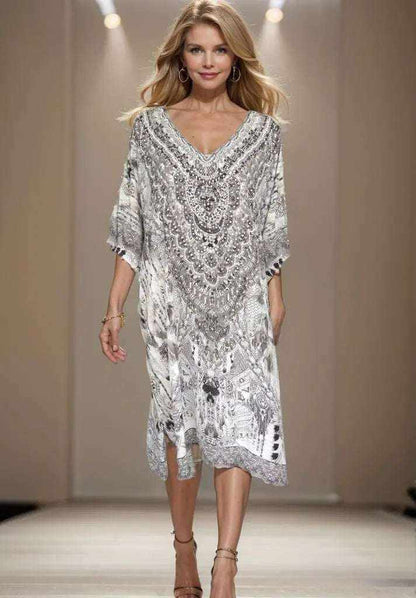 Woman wearing a knee-length 34 sleeve silk embellished dress with handsewn beadwork in silver and gold