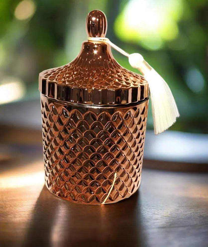 Rose Gold Geo Deluxe Soy Candle in a textured jar with lid and tassel on wooden surface