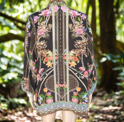 Black silk embellished shirt-capri with colorful floral patterns and intricate gold and silver beading seen from the back in outdoor setting