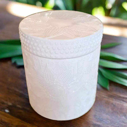 Lotus White Deluxe Soy Candle 400ml in decorative white jar with lid on wooden surface with green leaves background