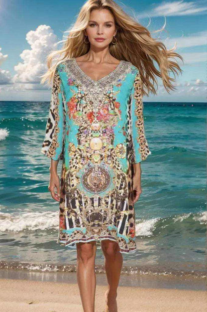 Woman wearing Garden Delight Aqua short silk embellished tunic dress standing on the beach with ocean background