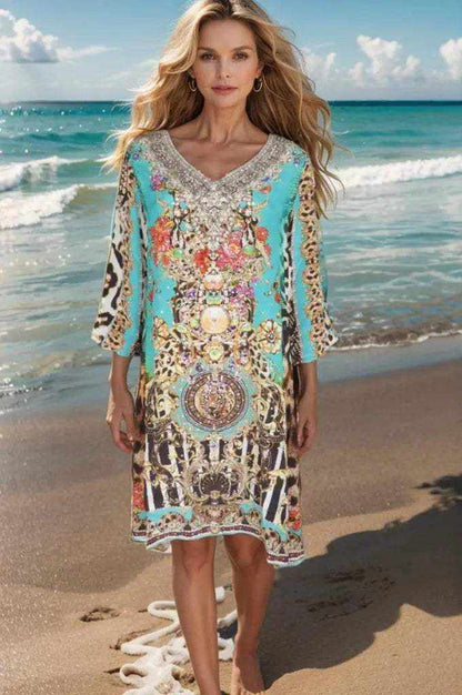 Woman wearing Garden Delight Aqua silk embellished tunic dress standing on beach with ocean background