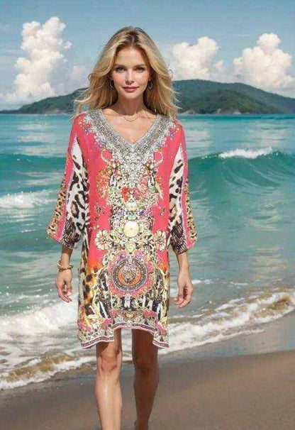 Woman wearing Garden Delight red silk embellished tunic dress with beadwork walking on the beach