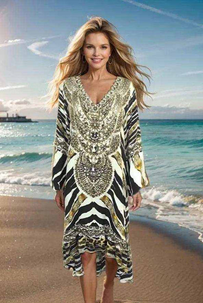 Woman wearing silk hi-low frill dress with animal print and beadwork walking on beach