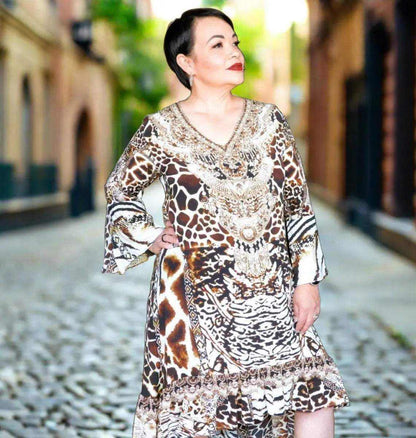 Woman wearing a luxurious silk hi-low frill dress with animal print and hand-sewn beadwork, featuring a V-neck and long split sleeves.