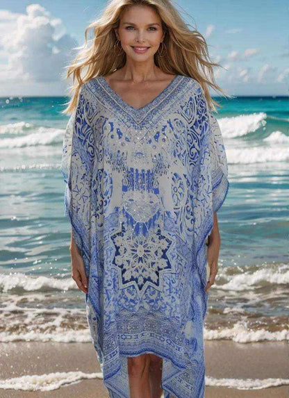 Woman wearing blue and white Garden Short Silk Embellished Kaftan with handsewn beadwork on a beach background