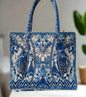 Large embellished tote bag with blue and white intricate patterns, padded handles, and zipper closure, designed for everyday use.