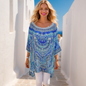 Woman in blue silk embellished kaftan top with high-low hem and white leggings.