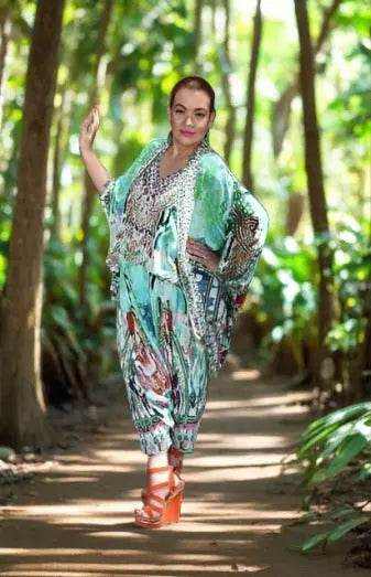 Woman wearing paradise green silk harem pants with hand-sewn beadwork walking in a forest setting