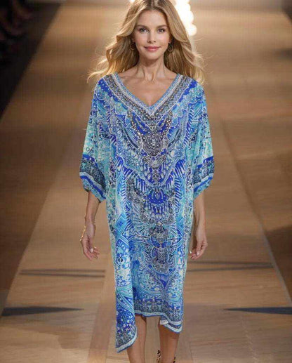 Woman wearing a blue 3/4 sleeve silk embellished dress with beadwork and V-neck walking on runway