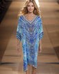 Woman wearing a blue 3/4 sleeve silk embellished dress with beadwork and V-neck walking on runway