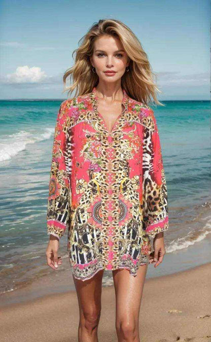 Woman wearing Garden Delight red silk embellished shirt with animal print standing on beach shore