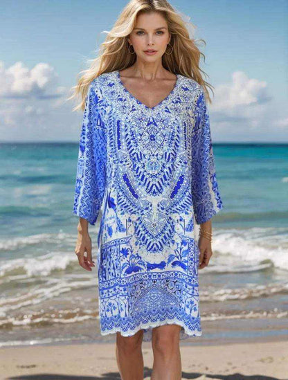 Woman wearing peacock silk hand beaded tunic dress on beach with blue and white design