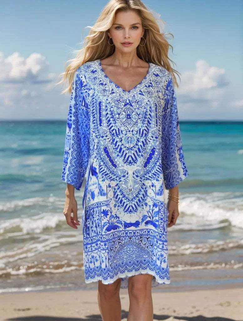 Woman wearing peacock silk hand beaded tunic dress on beach with blue and white design